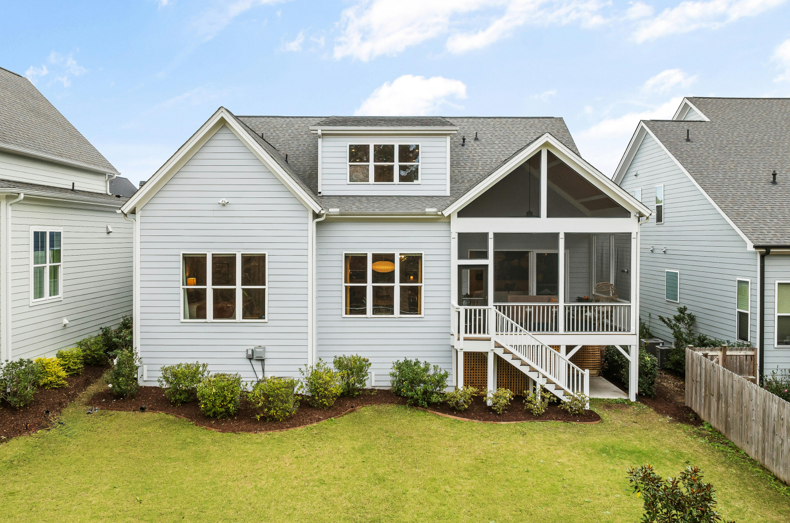 Back view of modern house with screened porch and yard