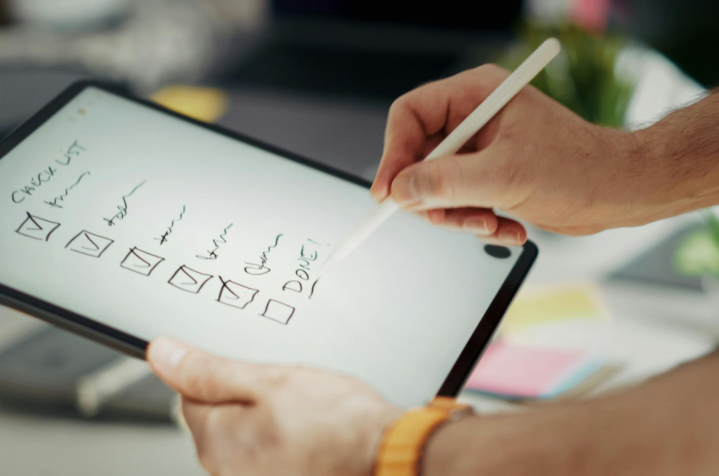 Person writing digital checklist on tablet with stylus