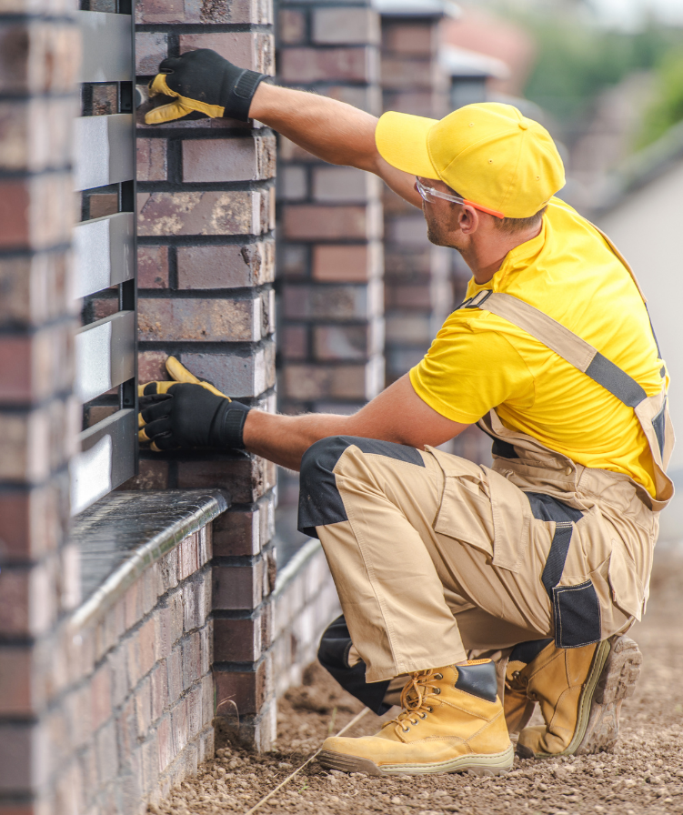 Worker installing exterior cladding on brick house wall