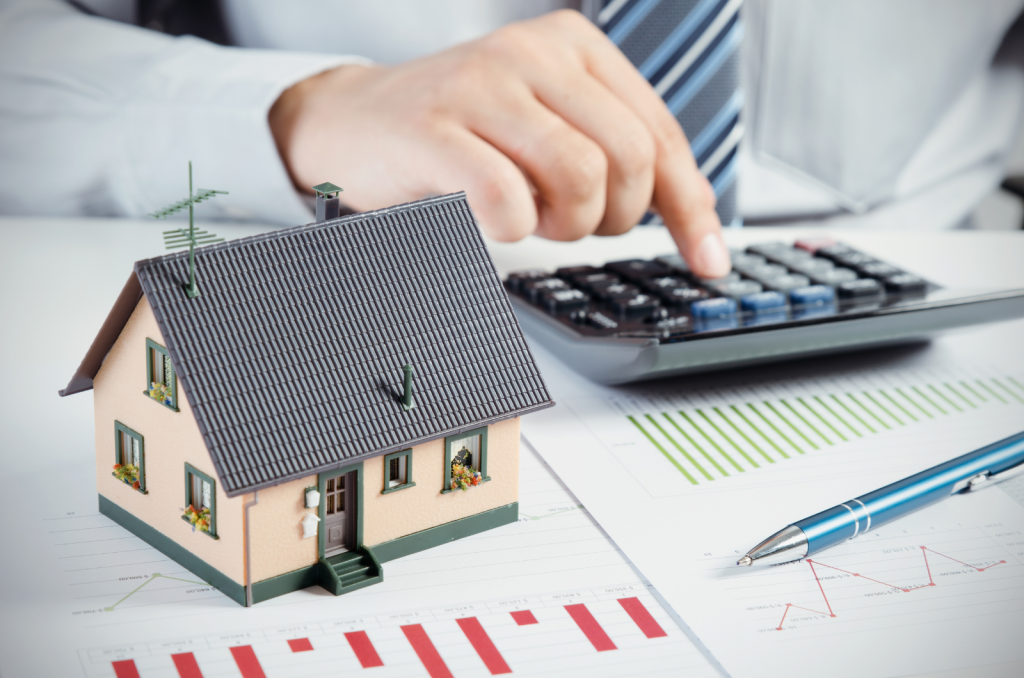 Person calculating home costs with house model and charts